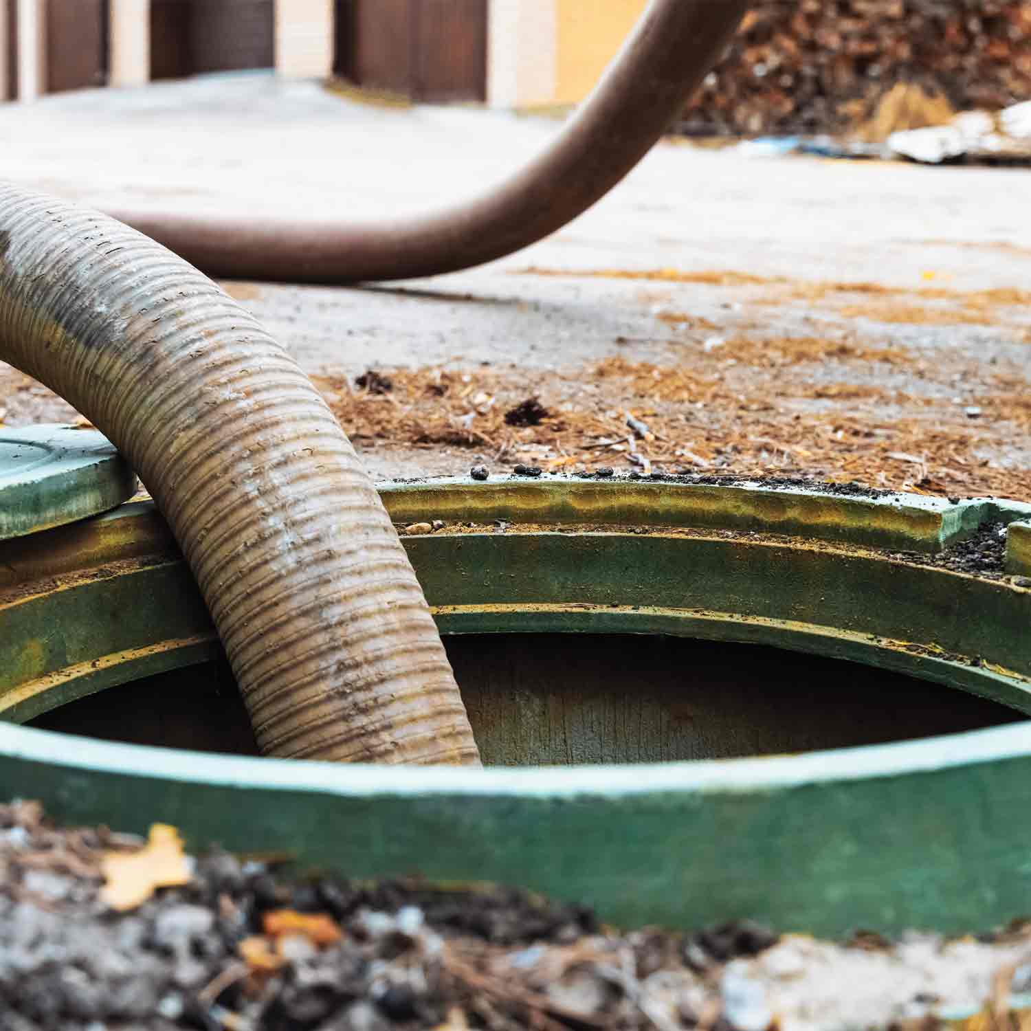 Precision Services hose inserted in open manhole for septic maintenance.