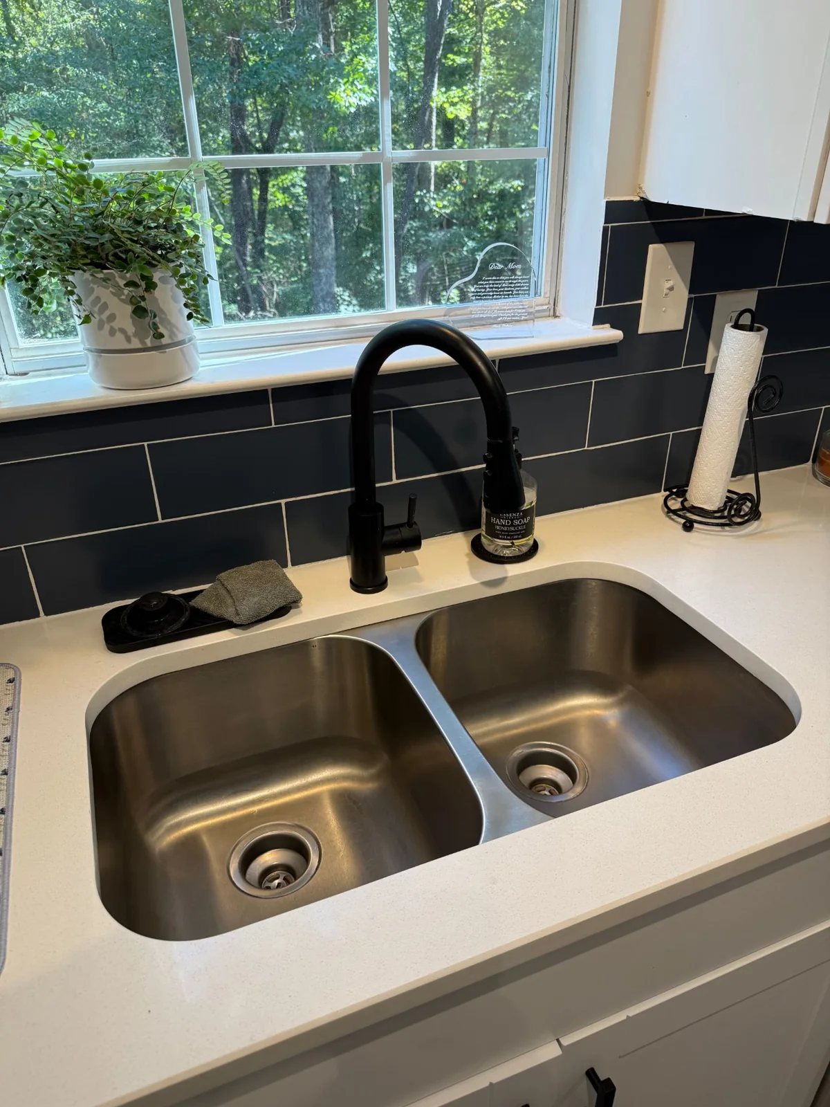 Double-bowl stainless kitchen sink with a black faucet after the drain repair.