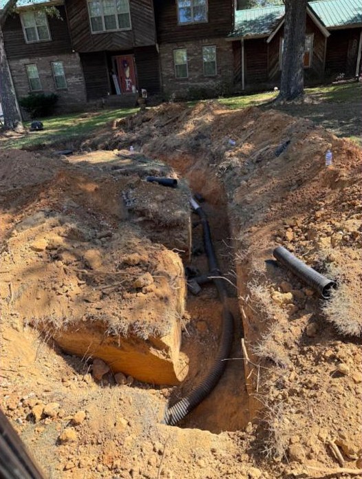 Trench in yard revealing drainage pipes for Precision Services.