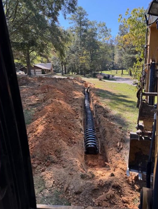 Black plastic septic pipe installed in deep trench.