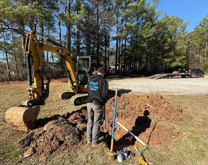 Precision Services technician beside a mini excavator at an underground line repair dig.