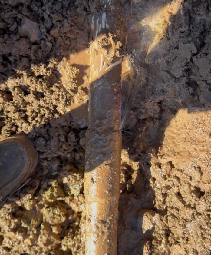 Water spraying from a leak in an exposed underground plumbing line.