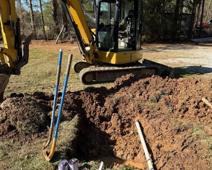 Mini excavator and shovels at an open trench over an underground line.